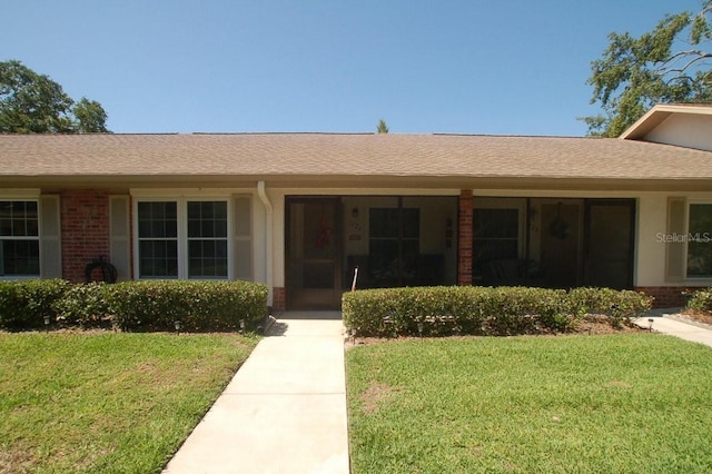 1126 Tarridon Ct, Dunedin, FL 34698 - property entrance featuring brick siding, a lawn, and roof with shingles