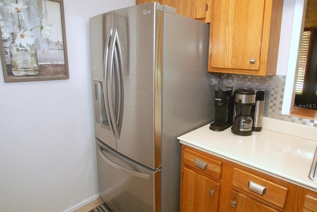 1126 Tarridon Ct, Dunedin, FL 34698 - kitchen with stainless steel fridge, brown cabinetry, light countertops, and tasteful backsplash