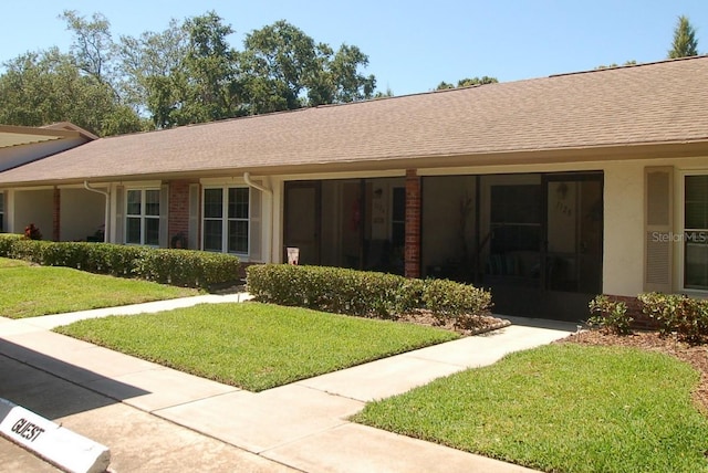 1126 Tarridon Ct, Dunedin, FL 34698 - view of front of home featuring a front yard, a shingled roof, and brick siding