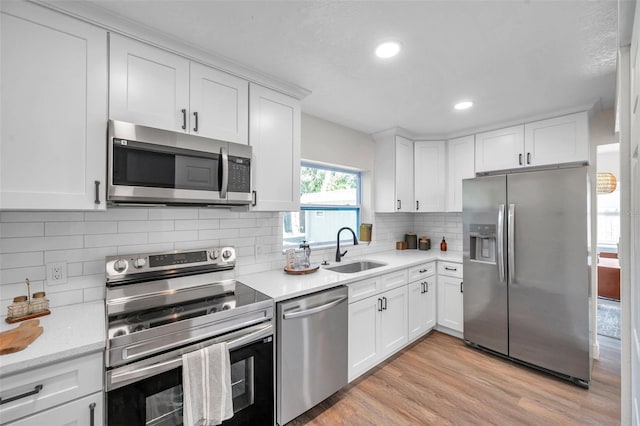 2078 Madrid Ct N, Clearwater, FL 33763 - kitchen featuring appliances with stainless steel finishes, a sink, white cabinetry, backsplash, and light wood-style floors