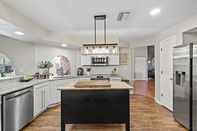 1914 Elk Spring Dr, Brandon, FL 33511 - kitchen featuring stainless steel appliances, a sink, arched walkways, white cabinets, and decorative backsplash