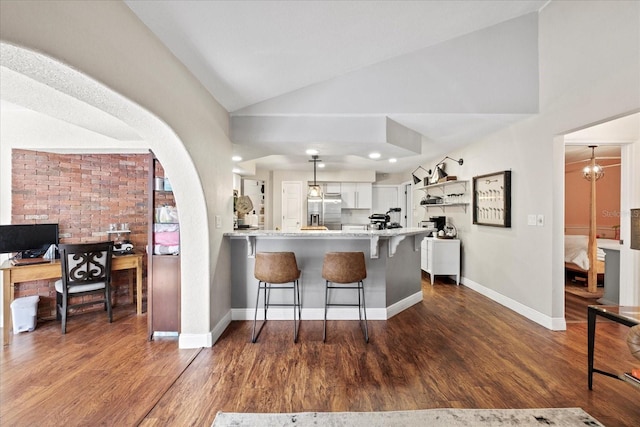 1914 Elk Spring Dr, Brandon, FL 33511 - kitchen with stainless steel fridge with ice dispenser, a peninsula, white cabinets, dark wood-style flooring, and a breakfast bar