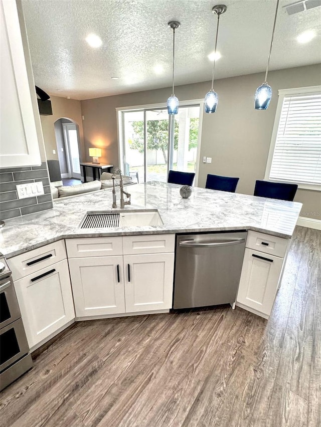 1147 Halapa Way, Trinity, FL 34655 - kitchen with appliances with stainless steel finishes, a sink, light wood-style flooring, a textured ceiling, and arched walkways