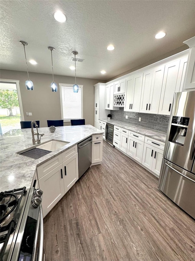 1147 Halapa Way, Trinity, FL 34655 - kitchen with appliances with stainless steel finishes, a sink, wood finished floors, white cabinets, and a textured ceiling