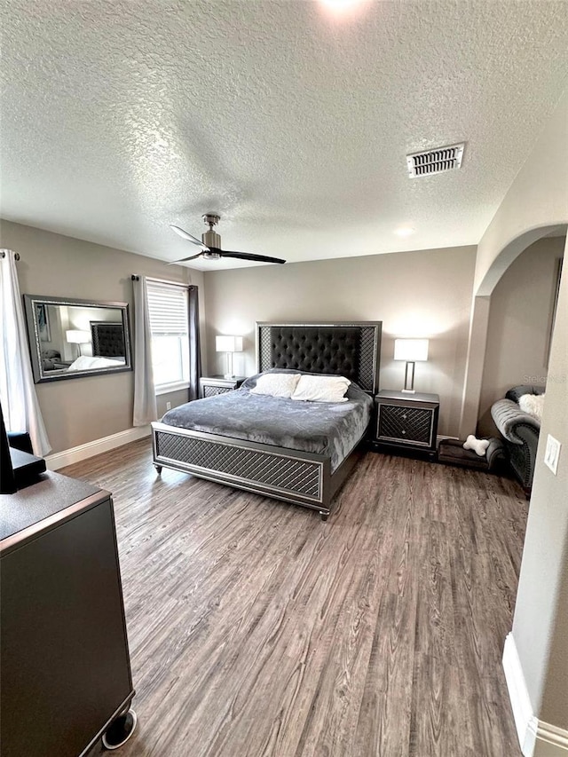 1147 Halapa Way, Trinity, FL 34655 - bedroom featuring wood finished floors, a textured ceiling, arched walkways, baseboards, and ceiling fan