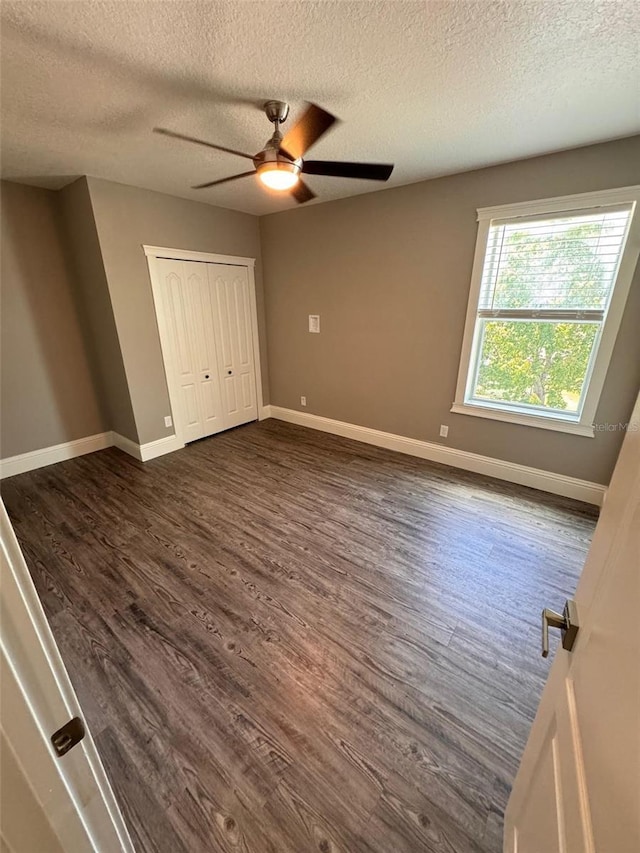 1147 Halapa Way, Trinity, FL 34655 - unfurnished bedroom featuring a textured ceiling, dark wood finished floors, baseboards, and a ceiling fan