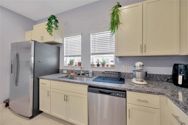 842 Tennyson Mill Cir, Tampa, FL 33619 - kitchen with stainless steel appliances, a sink, light tile patterned floors, and stone counters