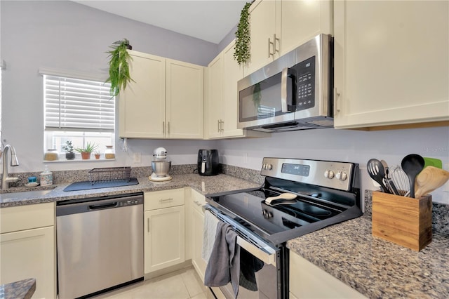 842 Tennyson Mill Cir, Tampa, FL 33619 - kitchen featuring appliances with stainless steel finishes, a sink, light tile patterned flooring, and light stone countertops