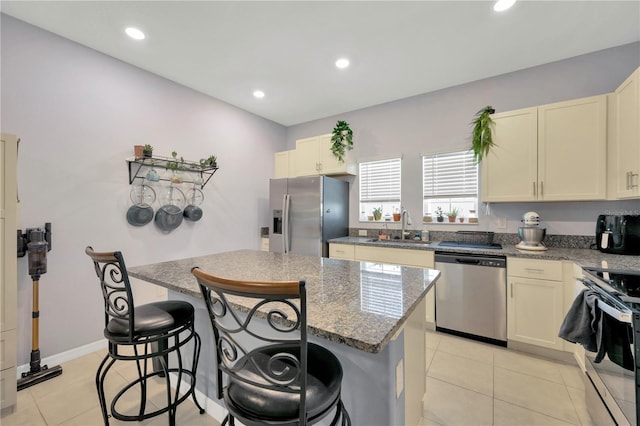842 Tennyson Mill Cir, Tampa, FL 33619 - kitchen with appliances with stainless steel finishes, a sink, a kitchen island, a breakfast bar area, and dark stone countertops