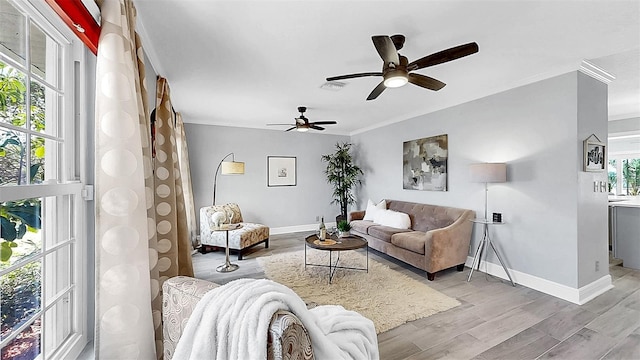 living area featuring crown molding, a ceiling fan, baseboards, and light wood-type flooring