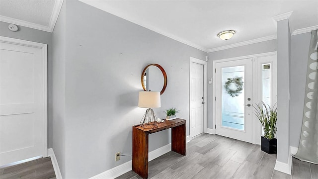 foyer entrance featuring wood finished floors, crown molding, and baseboards