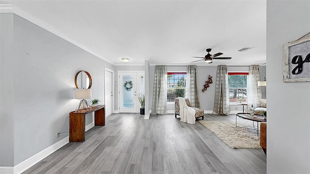 foyer with wood finished floors, ceiling fan, baseboards, and ornamental molding
