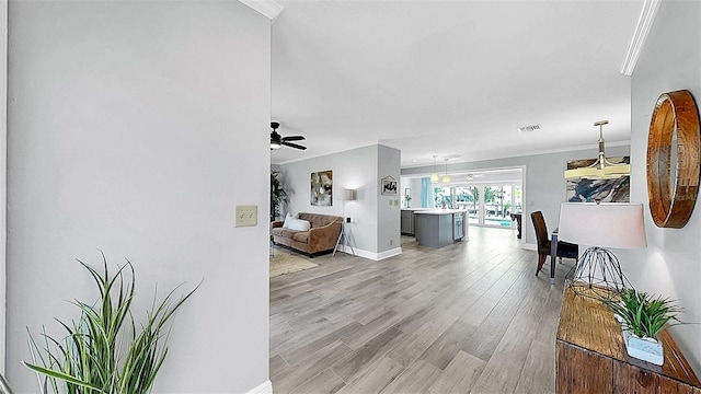 corridor with crown molding, baseboards, and light wood finished floors