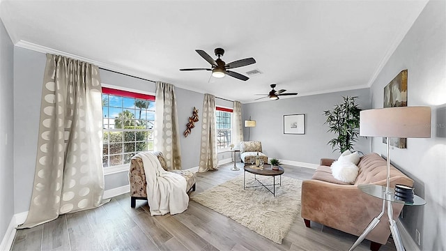 living area with ornamental molding, baseboards, a ceiling fan, and wood finished floors