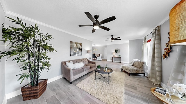 living area with a ceiling fan, baseboards, light wood-style floors, and ornamental molding
