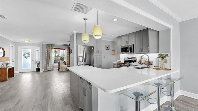 kitchen featuring appliances with stainless steel finishes, a sink, gray cabinets, crown molding, and light countertops