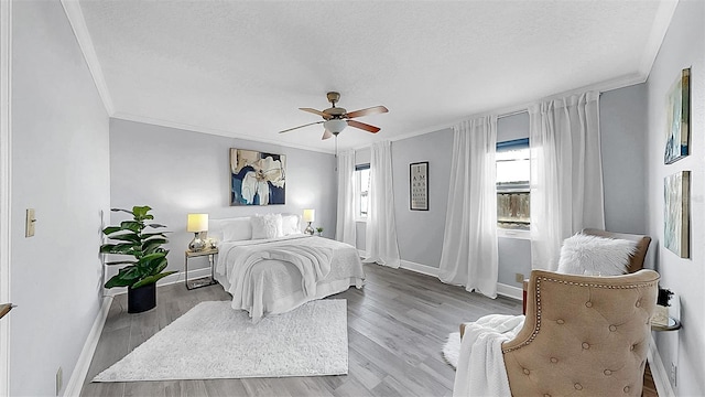 bedroom featuring a textured ceiling, baseboards, crown molding, wood finished floors, and ceiling fan
