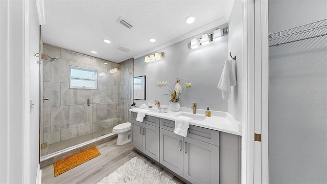 bathroom with wood finished floors, a stall shower, toilet, vanity, and recessed lighting