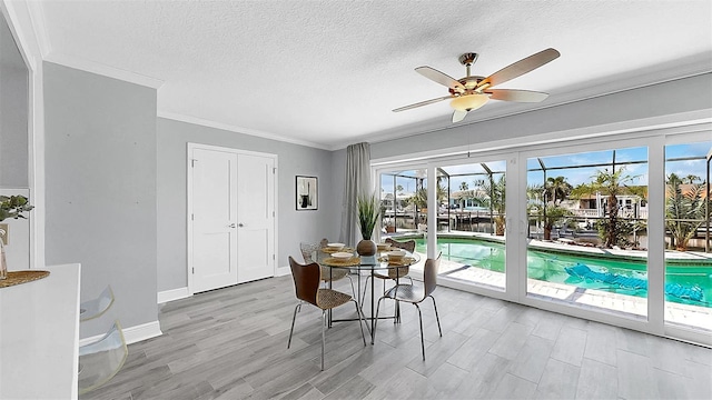 dining room with ceiling fan, crown molding, a textured ceiling, wood finished floors, and baseboards