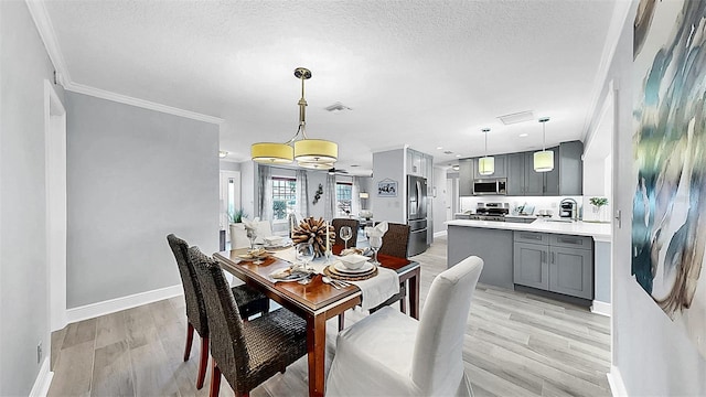 dining space featuring light wood-type flooring, baseboards, a textured ceiling, and crown molding