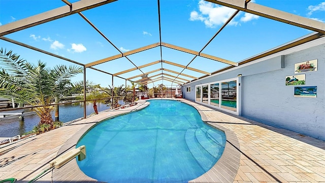 outdoor pool with a patio, a water view, and glass enclosure