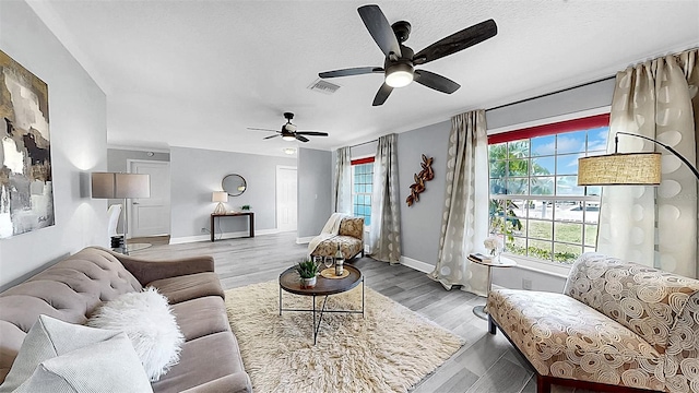 living area featuring ceiling fan, baseboards, and wood finished floors