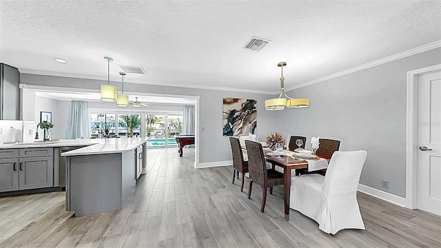 dining space featuring a textured ceiling, light wood finished floors, baseboards, ornamental molding, and recessed lighting