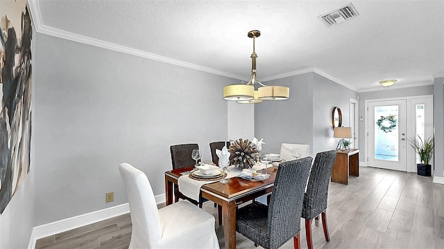 dining area with light wood-type flooring, baseboards, ornamental molding, and a chandelier