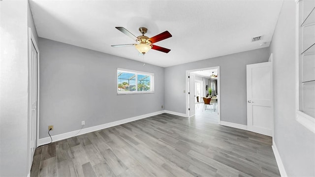 spare room with a ceiling fan, light wood-type flooring, and baseboards