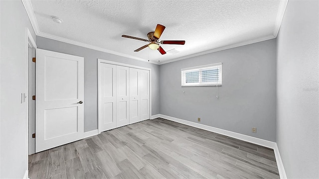 unfurnished bedroom with wood finished floors, a textured ceiling, ornamental molding, a closet, and baseboards