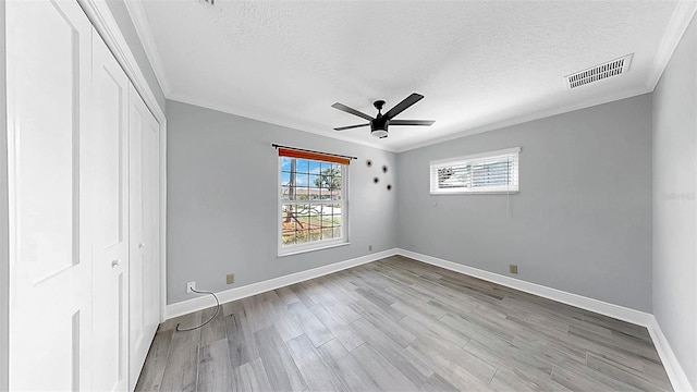 unfurnished bedroom with ornamental molding, a textured ceiling, wood finished floors, a closet, and baseboards