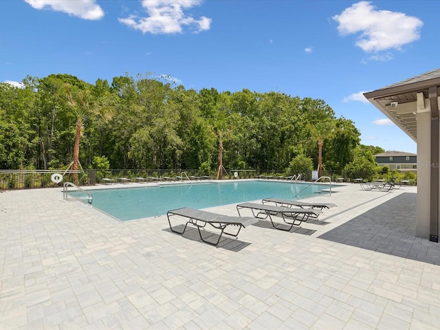 17729 Nectar Flume Dr, Land O Lakes, FL 34638 - community pool featuring a patio area, fence, and view of wooded area