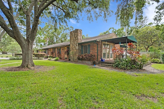 3005 W Sligh Ave, Tampa, FL 33614 - view of front of home with a front yard, a chimney, and brick siding