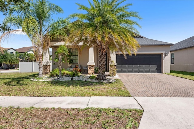 9931 Victory Gallop Loop, Ruskin, FL 33573 - view of front facade with decorative driveway, a garage, stucco siding, and a porch