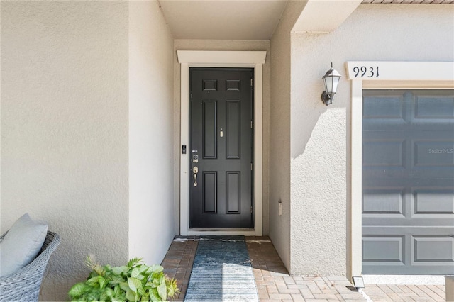 9931 Victory Gallop Loop, Ruskin, FL 33573 - doorway to property featuring stucco siding and a garage
