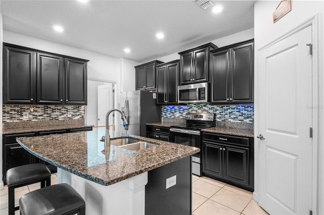 9931 Victory Gallop Loop, Ruskin, FL 33573 - kitchen with stainless steel appliances, dark cabinetry, a sink, a kitchen bar, and recessed lighting