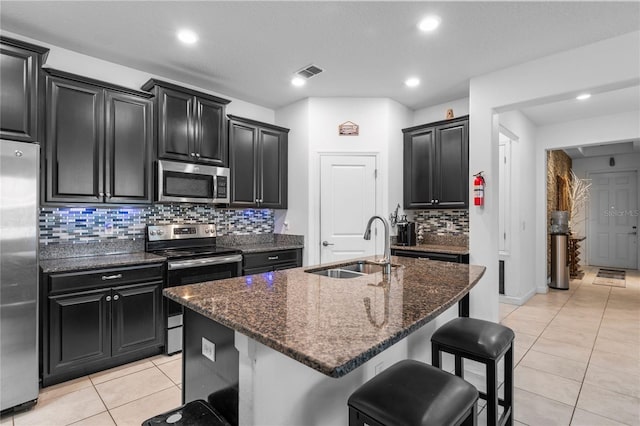 9931 Victory Gallop Loop, Ruskin, FL 33573 - kitchen featuring appliances with stainless steel finishes, a sink, dark cabinets, light tile patterned floors, and tasteful backsplash