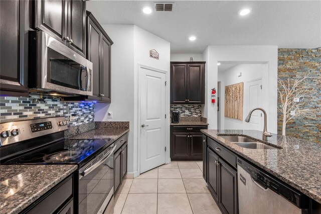 9931 Victory Gallop Loop, Ruskin, FL 33573 - kitchen with stainless steel appliances, a sink, decorative backsplash, dark stone counters, and light tile patterned floors