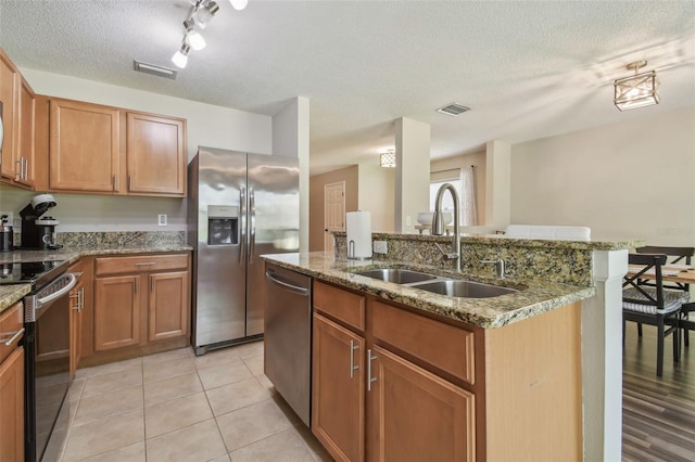 4528 Winding River Way, Land O Lakes, FL 34639 - kitchen with appliances with stainless steel finishes, a sink, a textured ceiling, an island with sink, and light stone counters