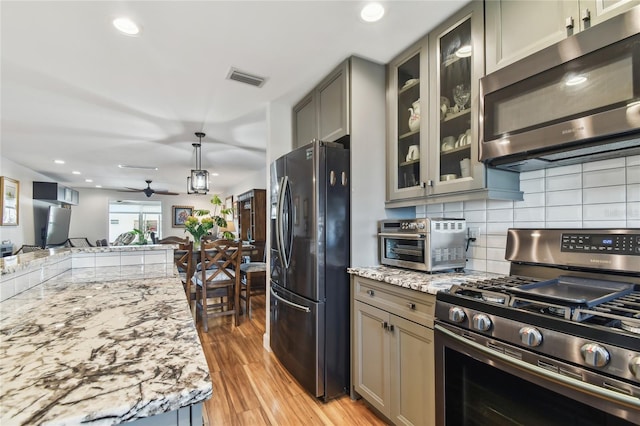 2960 59th St S Unit 614, Gulfport, FL 33707 - kitchen with stainless steel appliances, open floor plan, light stone countertops, light wood-style floors, and backsplash