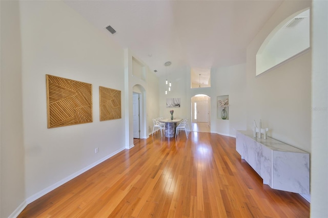 14502 Pond Cypress Way, Tampa, FL 33626 - hallway featuring arched walkways, high vaulted ceiling, light wood-style floors, and baseboards