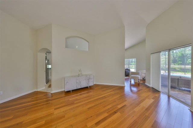 14502 Pond Cypress Way, Tampa, FL 33626 - empty room with light wood finished floors, arched walkways, baseboards, and high vaulted ceiling