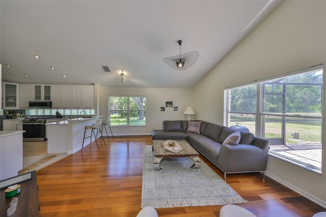 14502 Pond Cypress Way, Tampa, FL 33626 - living area featuring light wood-type flooring, baseboards, high vaulted ceiling, and recessed lighting