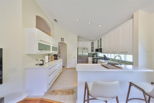 14502 Pond Cypress Way, Tampa, FL 33626 - kitchen with stainless steel appliances, a peninsula, glass insert cabinets, a sink, and a kitchen bar