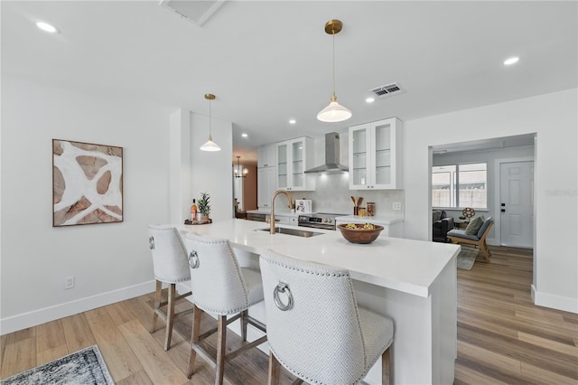 2815 Golfview Dr, Melbourne, FL 32901 - kitchen with a sink, wall chimney range hood, white cabinets, a peninsula, and light wood-type flooring