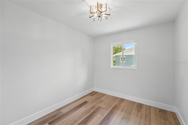 2815 Golfview Dr, Melbourne, FL 32901 - unfurnished room with baseboards, light wood-style floors, and a chandelier