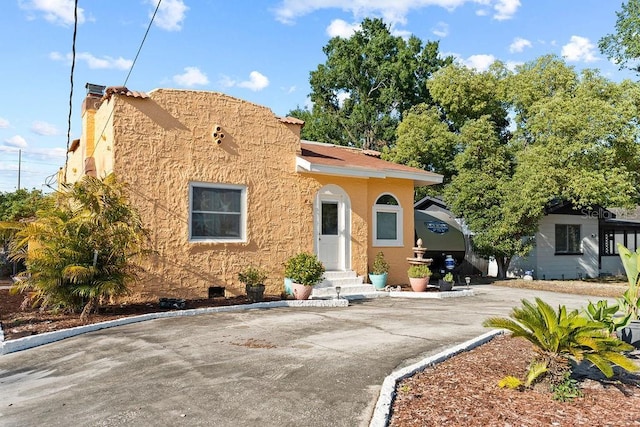 view of front of home with entry steps, a chimney, and stucco siding