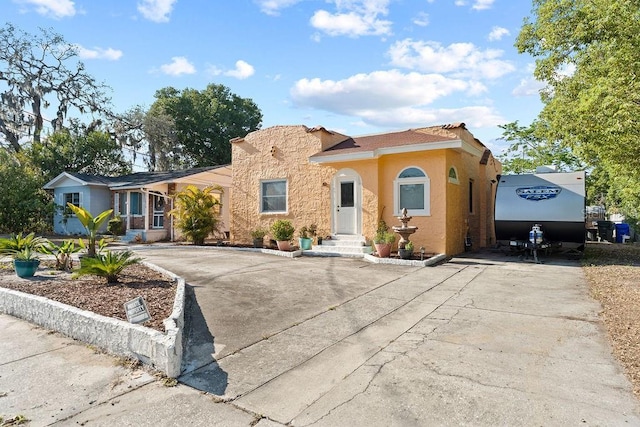 mediterranean / spanish house with concrete driveway and stucco siding