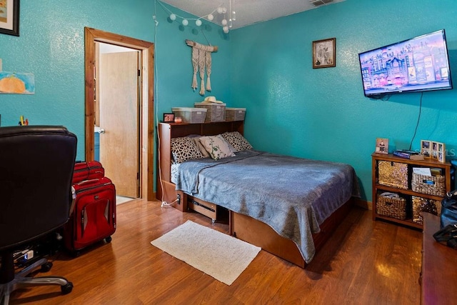 bedroom featuring a textured wall and wood finished floors