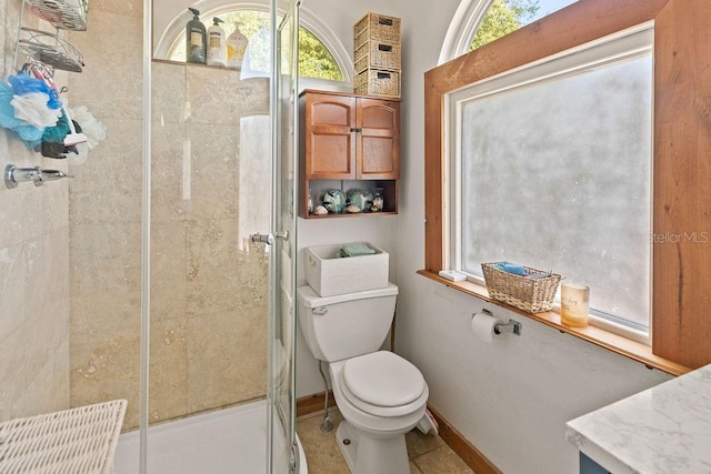 bathroom featuring a shower stall, plenty of natural light, toilet, and baseboards